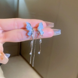 Close-up of blue butterfly wing drop earrings with silver tassels and crystal accents