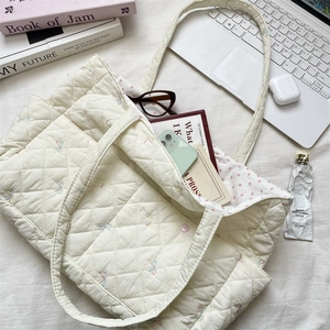 Top view of quilted cream tote bag with floral embroidery and pink star pattern lining