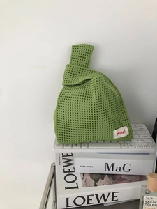 Close-up of grass green hollow-out knit handbag with honeycomb texture and woven label