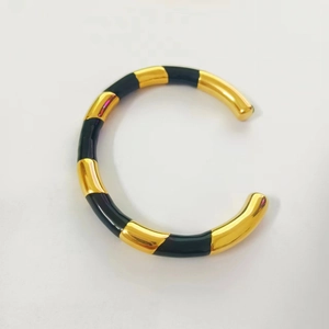 Detail of 18k gold plated open cuff bracelet with black enamel checkerboard pattern