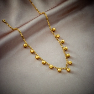 Elegant gold titanium steel necklace with small beads on silk background for women