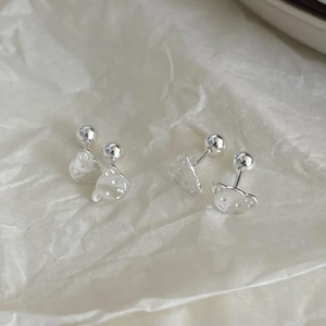 Detailed view of sterling silver bear stud earrings on minimalist beige paper background