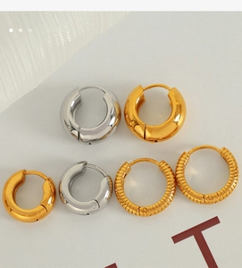 Close-up of sleek gold and silver stainless steel hoop earrings in various textures