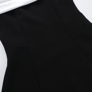 Detailed view of black and white contrast stitching on a slim-fit off-shoulder dress