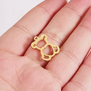 Detailed close-up of a small golden hollow bear pendant held in hand for scale