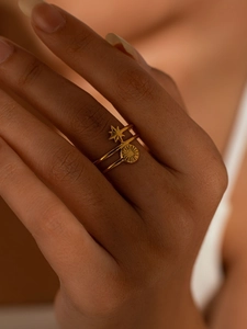 Detailed view of stacked gold titanium rings featuring star and sunburst designs