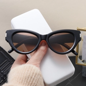 Detail of black cat-eye sunglasses with silver metal hinges and a white leather case