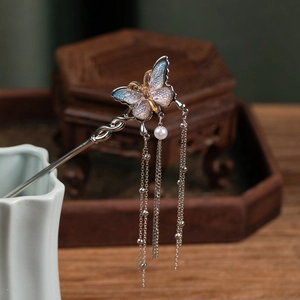 Macro shot of silver hair stick with blue butterfly detail and pearl tassels