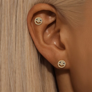 Macro detail of gold smiling face earrings with blue and white pavé cubic zirconia