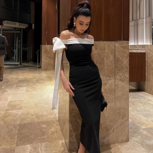 Detail of elegant black off-shoulder dress featuring a white oversized shoulder bow accent