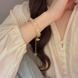 Detail of beaded bracelet with golden butterfly pendant and tassel on model wrist
