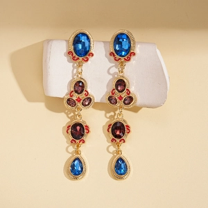 Detail of vintage Baroque earrings with blue and purple gemstones on golden metal
