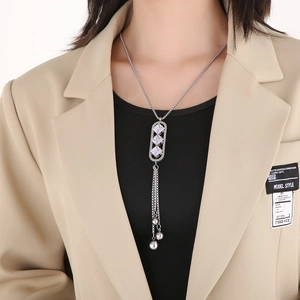 Close-up of silver tassel necklace with three cubic zirconia stones and metal ball fringe