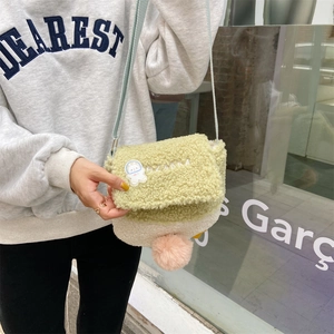 Detail of plush lamb wool crossbody bag with astronaut patch and soft pompom decoration