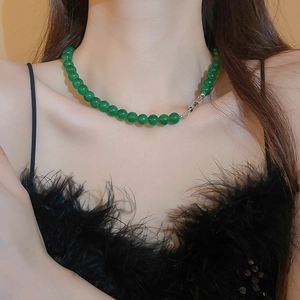 Gros plan du collier de perles vert émeraude avec finition polie sur mannequin en noir