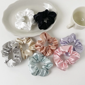 Set of 8 colorful silk satin hair scrunchies displayed on a white ceramic tray