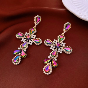 Detail shot of vintage golden cross earrings with colorful rhinestones on silk