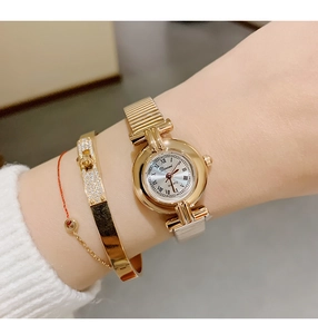 Close-up of DINIMI retro gold watch on wrist paired with a sparkling crystal bangle
