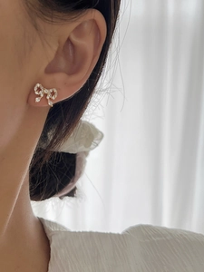 Close-up of sparkling crystal bow earrings with a teardrop zircon on a model's ear