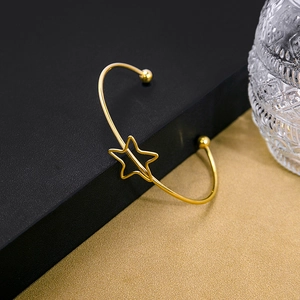 Detailed shot of a gold star-cutout open cuff bracelet on a luxury black and gold stand
