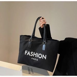 Detail der schwarzen Canvas-Tragetasche mit Fashion-Paris-Aufdruck und Ledergriffen
