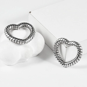 Vintage heart shaped earrings with silver scale texture displayed on white pedestals