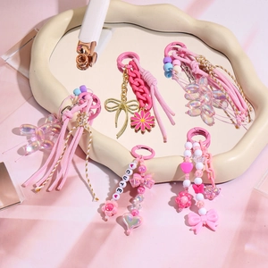Pink heart keychain set with cute beads, tassels, and balloon dog charms on a tray