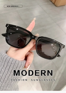 Detail shot of black square sunglasses with metallic rivet accents on the frame