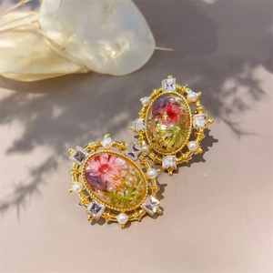 Macro detail of vintage 18K gold earrings with dried flowers, pearls and crystals