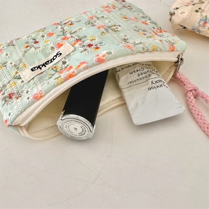 Detail of floral embroidery on light green cosmetic bag with pink braided handle