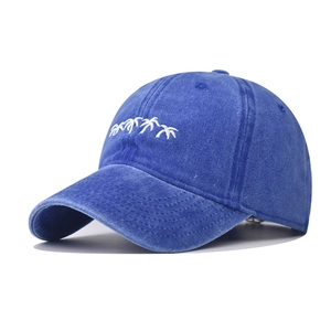 Détail de la broderie de cocotiers blancs sur casquette de baseball en denim délavé