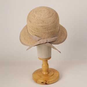 Detail of handcrafted raffia sun hat with bow on an elegant wooden display stand