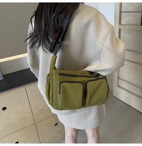 Olive green multi-pocket canvas crossbody bag with adjustable wide strap worn by a model
