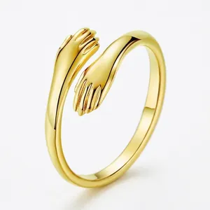 Minimalist gold hugging ring for lovers featuring a hands entwined design and glossy finish