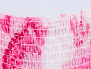 Gros plan détaillé sur le tissu smocké rose avec motifs floraux en impression tie-dye