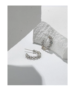 Dettaglio di orecchini a C in argento S925 con perle di labradorite sfaccettate su pietra
