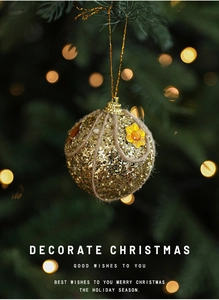 Detail of a gold sequin Christmas ball with rope texture hanging on a festive tree
