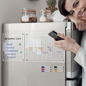Smiling woman using magnetic acrylic weekly planner and grocery list set on a fridge