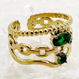 Detail shot of a golden multi-layer adjustable ring featuring green emerald stones