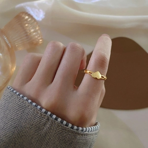Élégante bague cœur dorée au doigt d'une femme avec une esthétique française épurée