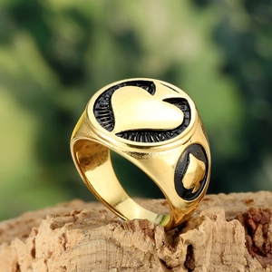 Close-up of gold heart signet ring with black enamel details on a cork stand