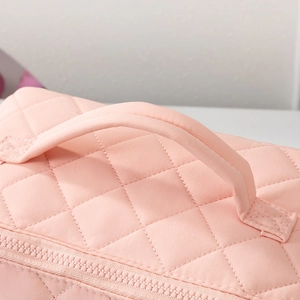 Macro shot of the sturdy handle and quilted pattern on a pink waterproof vanity bag