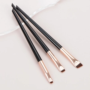 Close-up of three professional angled eyeliner and eyebrow brushes with rose gold ferrules