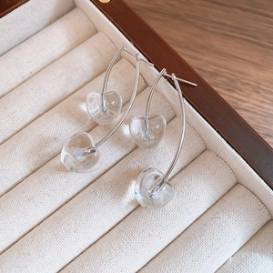 Detailed shot of elegant silver cherry drop earrings with clear glass charms in a jewelry box