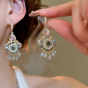 Close-up of vintage gold tassel earrings with colorful gemstones and gray crystal beads