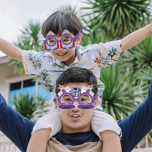 Father and son wearing space themed rocket and astronaut paper party glasses outdoors