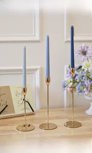 Three gold candlesticks with blue taper candles in a modern European interior setting