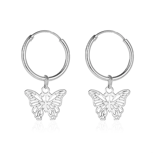 Macro view of silver hollow butterfly pendant hanging on smooth circular hoop earrings