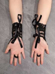 Detail of black lace gloves with satin bow and finger loop for Halloween bridal party