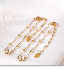 Macro view of 18k gold PVD plated stainless steel butterfly charm and bead chain texture